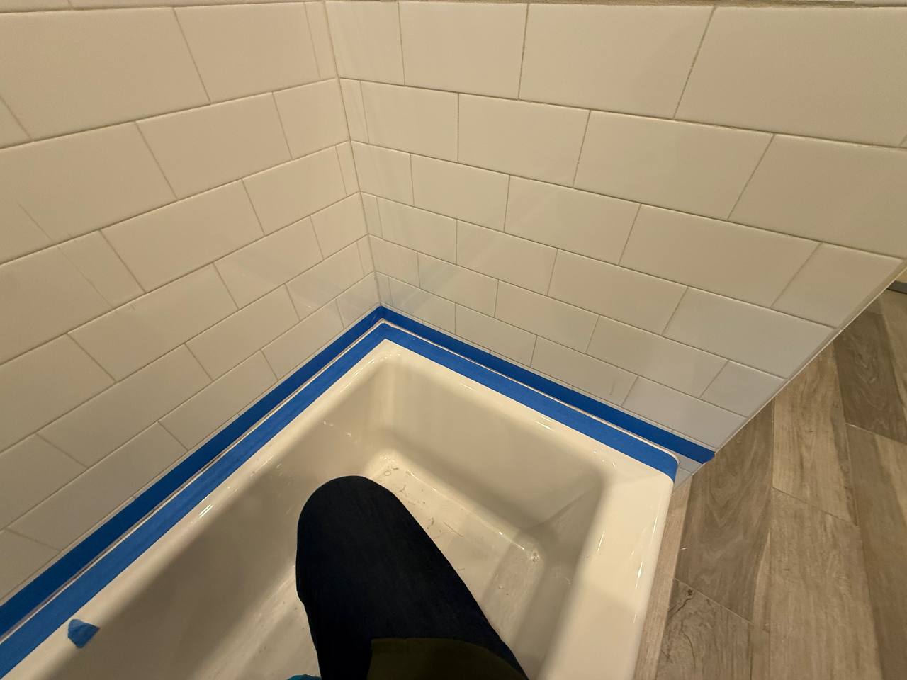 Bathtub surround with white subway tile and dark grout accent