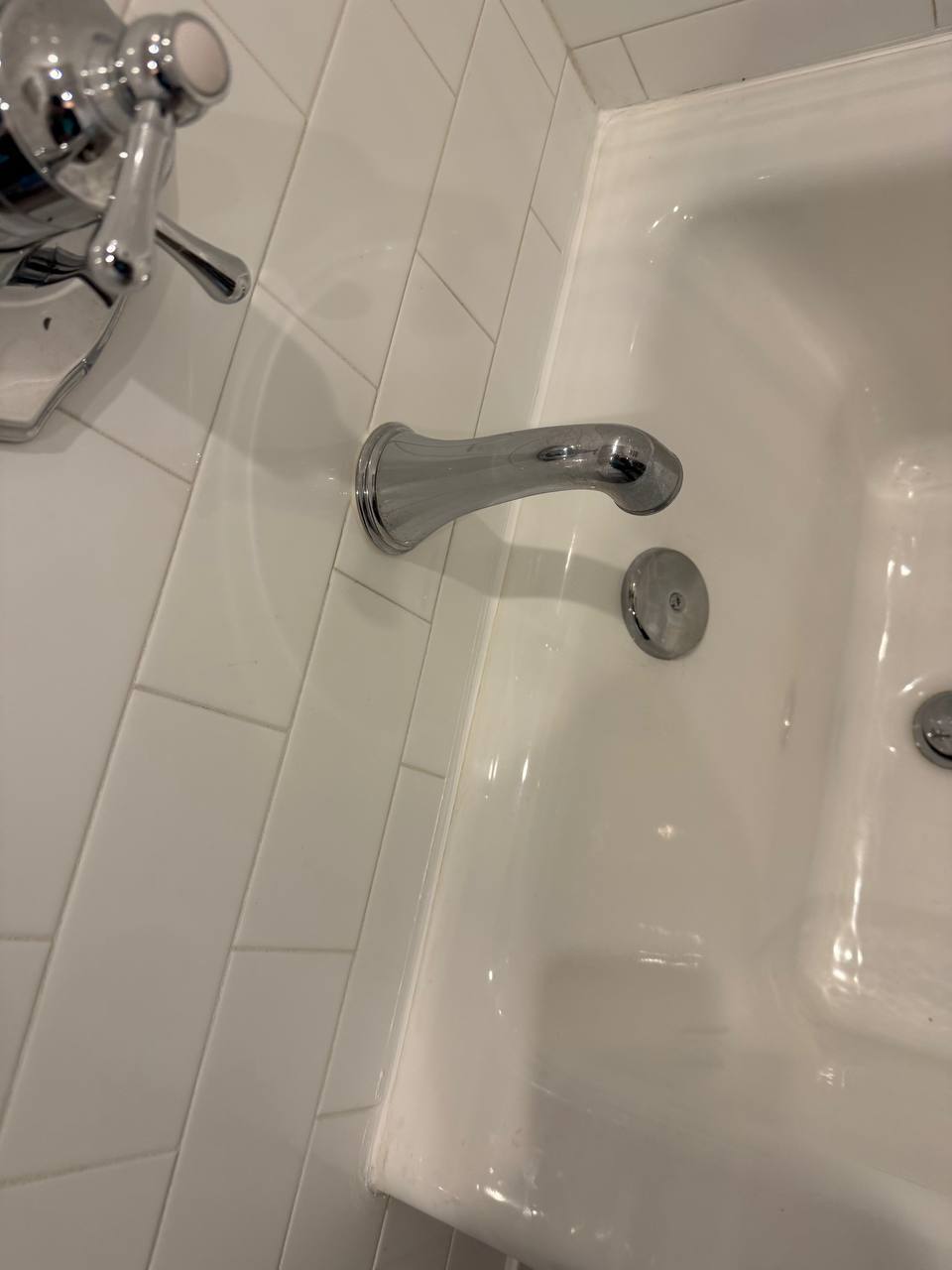 New chrome bathtub faucet installation with handheld shower attachment