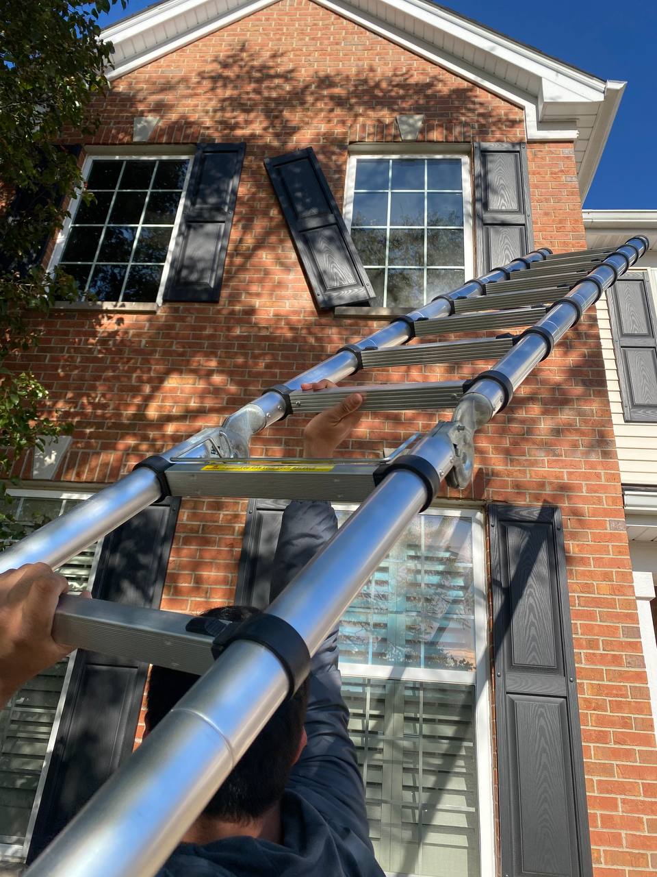 Exterior gutter and soffit inspection from ladder on brick home