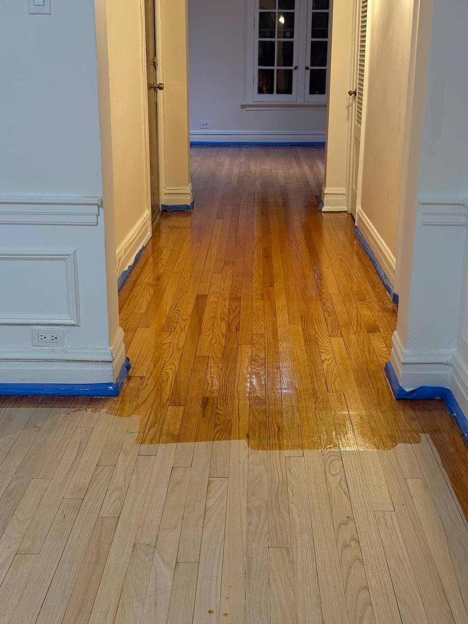 Hardwood floor staining in progress showing rich medium-brown color application