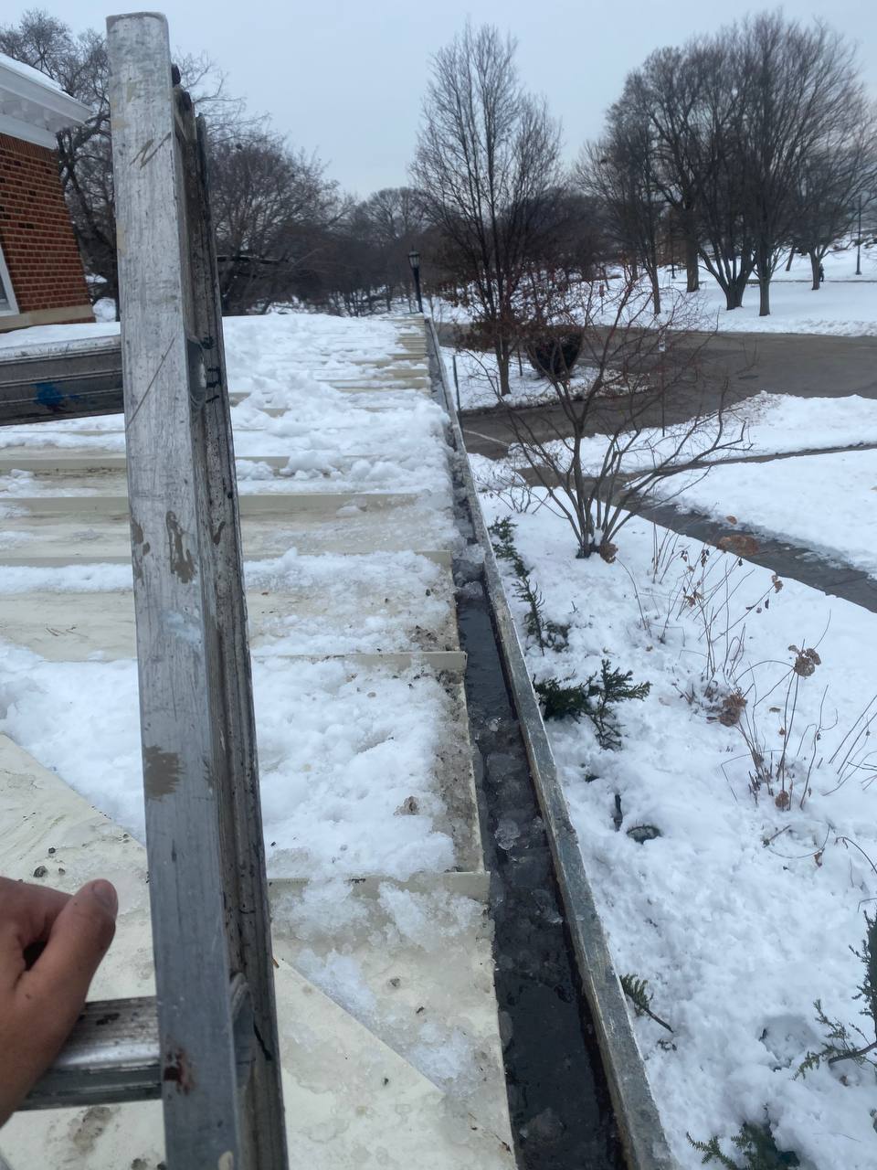 Winter roof and gutter inspection on snow-covered suburban home