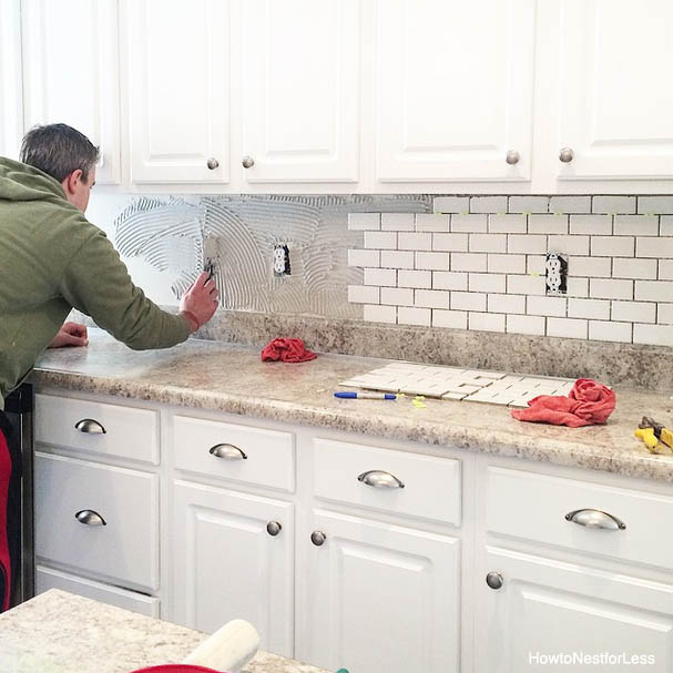 Herringbone pattern tile backsplash installation in a modern kitchen
